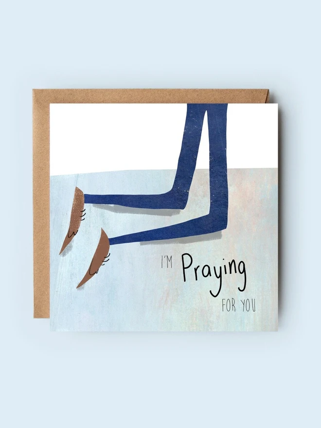 'praying for you' illustrated card. card photographed against plain blue backdrop.