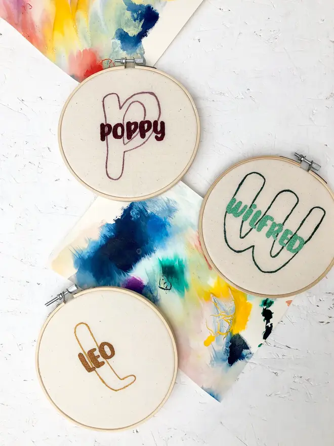 personalised name and initial embroidered hoop. three cotton hoops embroidered with names poppy, wilfred and leo respectively.