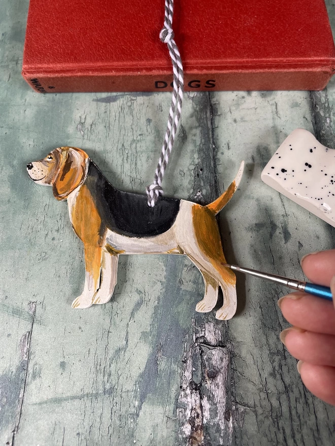 Beagle Dog Memory decoration with a hand adding finishing touches with a paintbrush