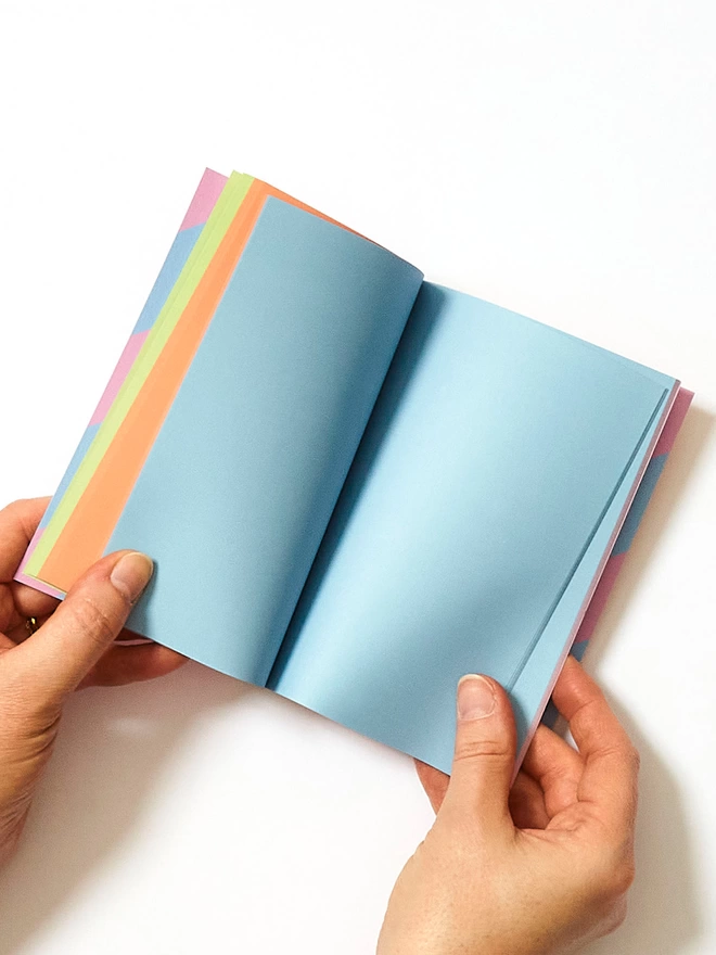 Inside the duo notebooks, one notebook has plain coloured pages, through out the notebook there are sections of green, orange, blue, and lilac plain coloured pages.