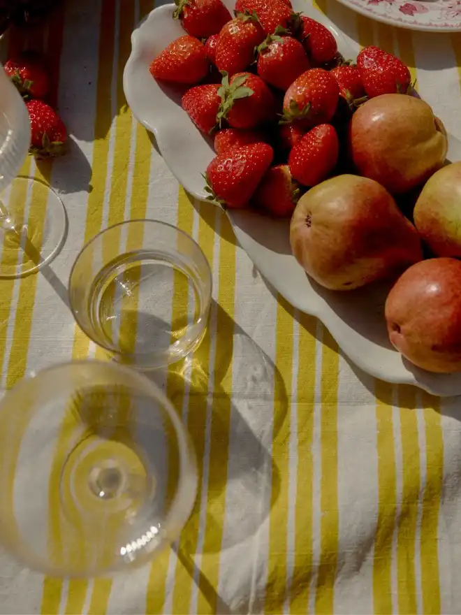 Yellow stripe tablecloth with strawberries and pear on a plate