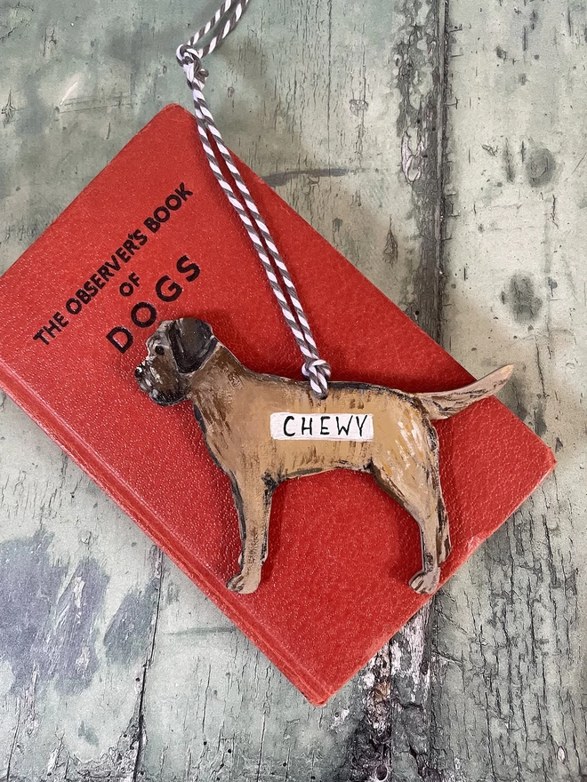A hanging  border terrier decoration, with the name Chewy on, placed onto a book about dogs