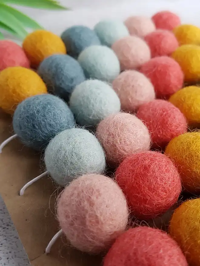 A pastel pom pom garland wrapped around a display card.