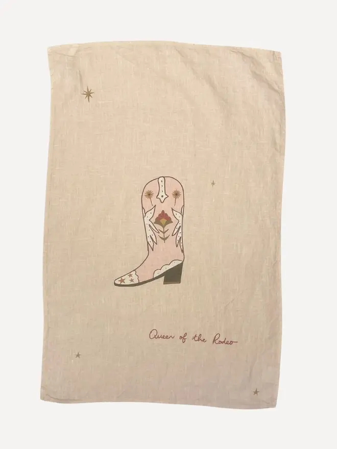 'Boots Are Made For Walking' Linen Tea Towel, a linen tea towel with a boot motif on it sitting on a plain white surface. 