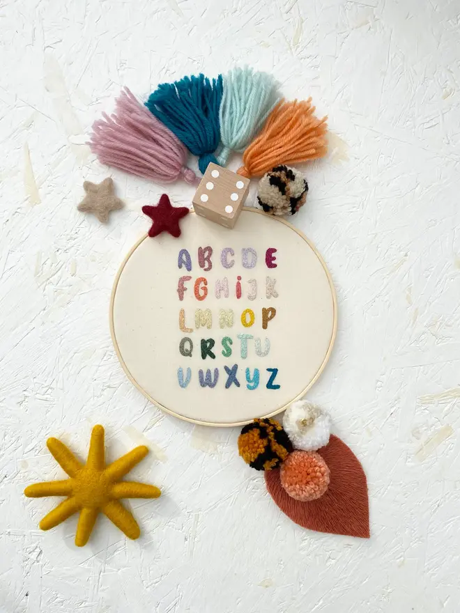 letters of the alphabet embroidered hoop. colourful stitch alphabet hoop on child's bedroom shelf.