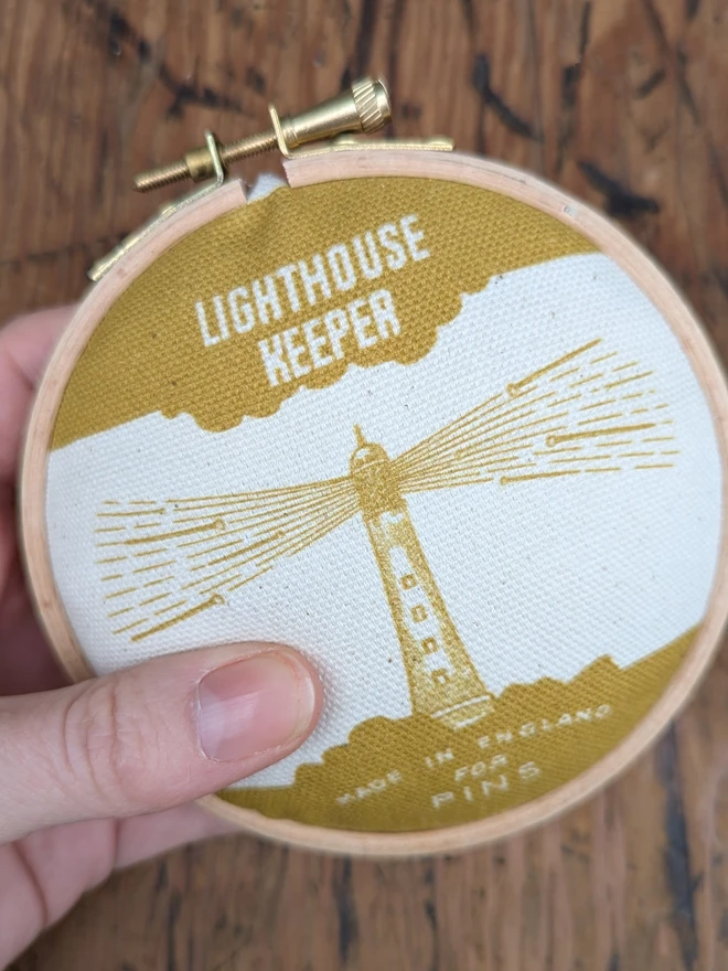 Hand holding mustard lighthouse keeper pin cushion
