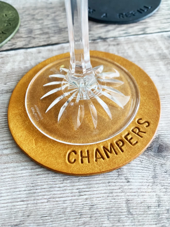 'Champers' hand stamped on Buttercup leather coaster.