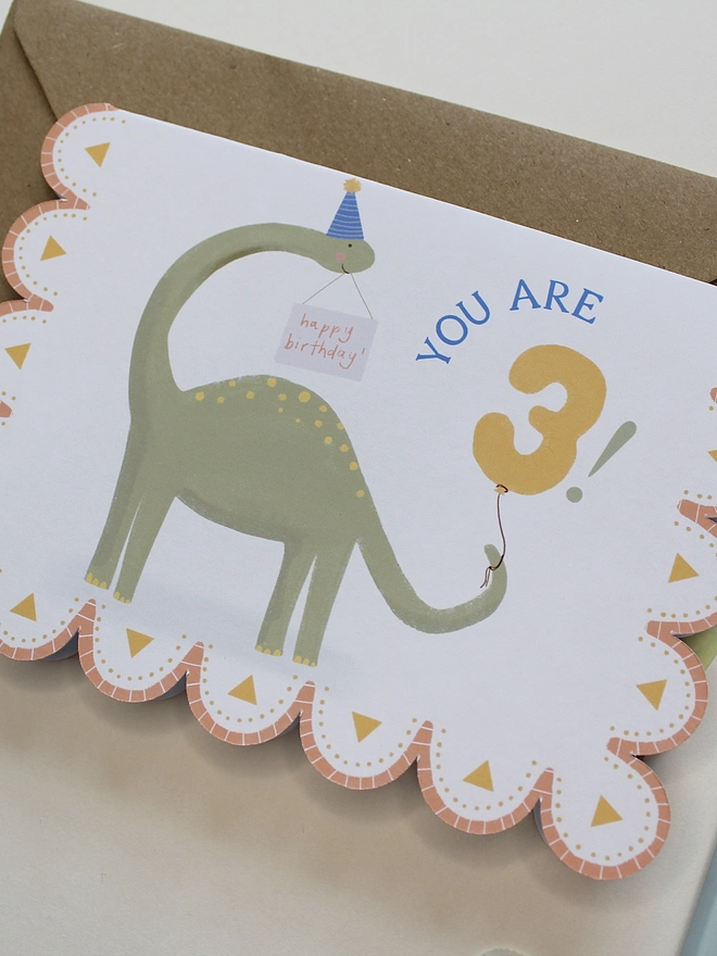 illustrated dinosaur birthday card. scallop edged card illustrated with stegosaurus.