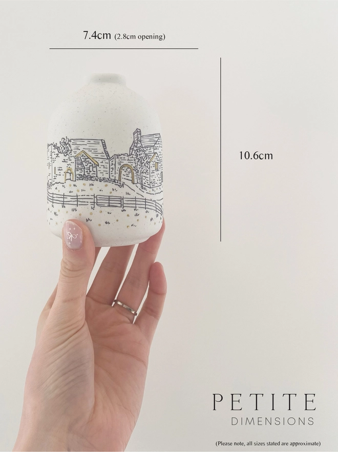 The dimensions of a ceramic vase with a hand drawn black illustration of a wedding venue