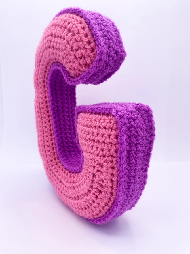 Crochet cushion shaped like the letter G in Pink and Magenta