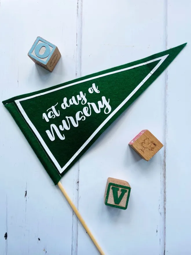 Mini pennant flag in green and white with the wording 1st day of nursery