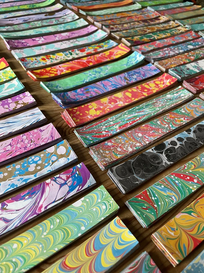 Hand-marbled paper chain strips laid out in rows