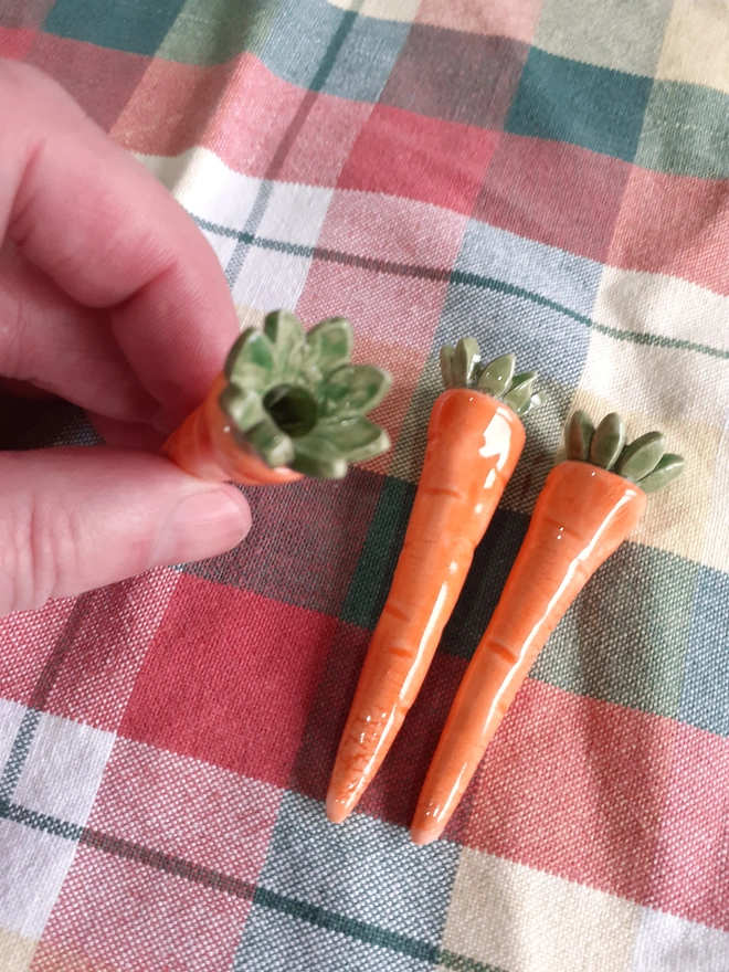 Detail view showing the candle opening inside a ceramic carrot candleholder sized to fit a standard birthday cake candle.