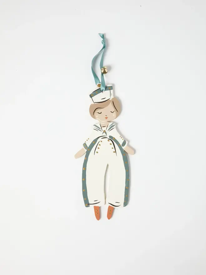 Sailor Heart Tree Dancer. wooden hanging sailor boy decoration with a white sailor hat, cream and duck egg blue jumpsuit with gold buttons and orange shoes, blue ribbon with a jingle bell, on a white background