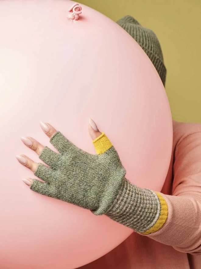 Women's Lambswool Fingerless Gloves, a woman wearing a pair of fingerless gloves holding a balloon. 