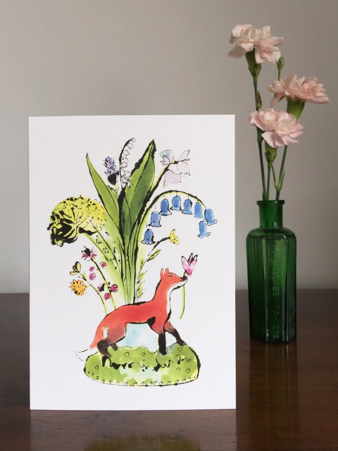 A greeting card featuring a fox with some wild flowers