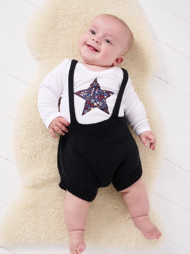 a baby wearing a liberty starry print star white bodysuit