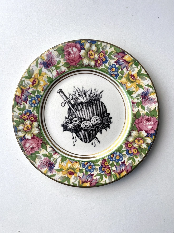 a vintage plate with an ornate border and in the centre is an old illustration of a beautiful sacred heart