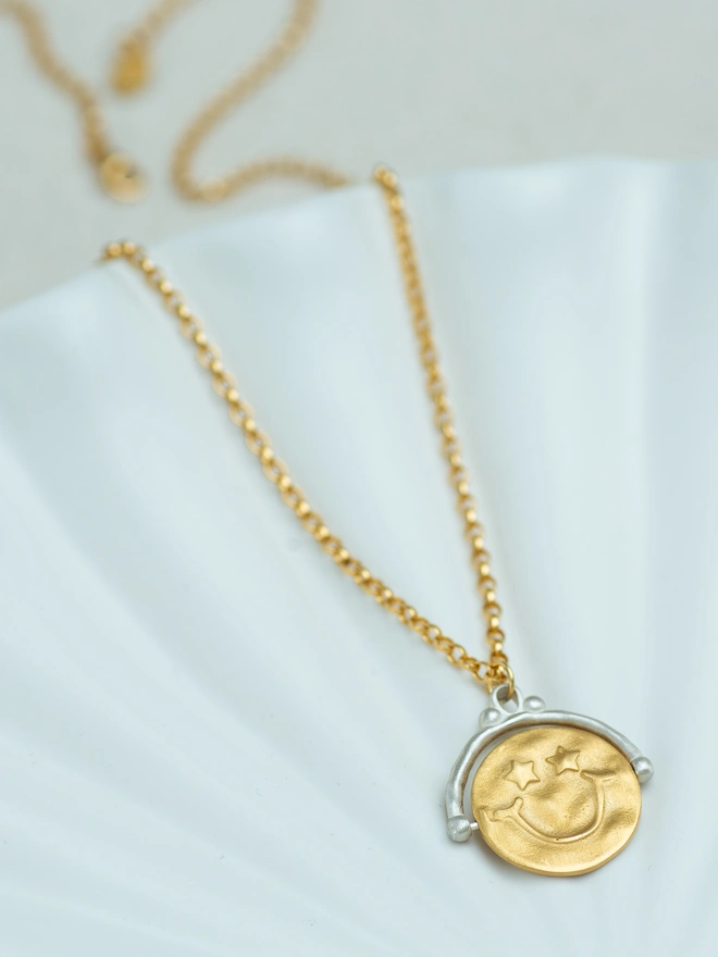 This two-tone spinner necklace features a star-eyed smiley on one side and “choose happy” on the other — a gentle reminder to pause and breathe. Crafted in sterling silver and gold plate, this tactile spinner pendant is perfect for anxious hands. A meaningful fidget necklace designed for everyday comfort, mindfulness and feel-good style.