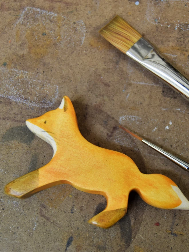 wooden fox cub being painted on a painting board