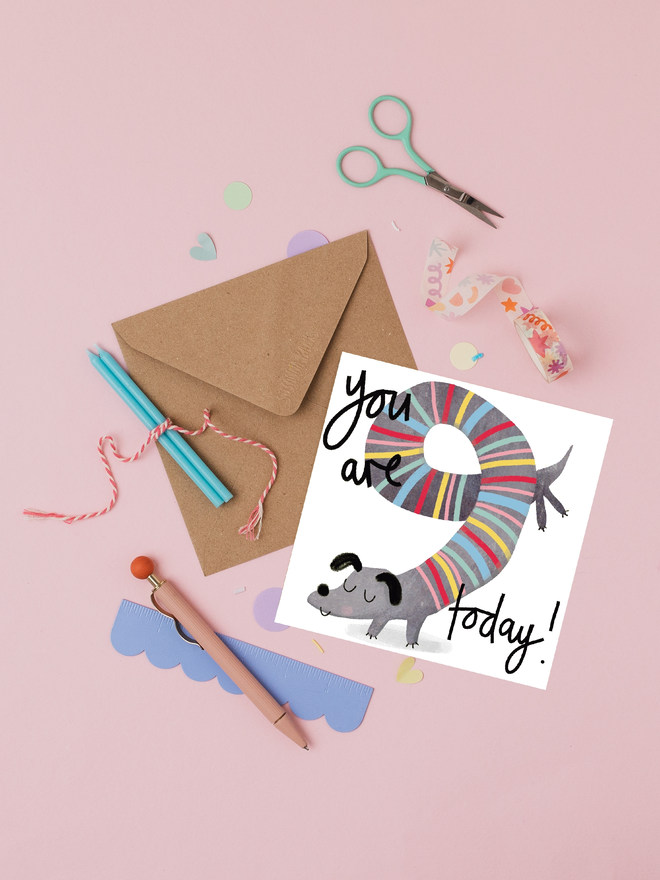 '9 today' illustrated birthday card. birthday card featuring a stripy sausage dog shaped into the number 9.