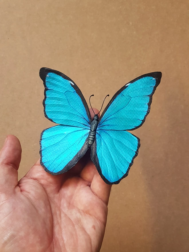 Handmade paper blue morpho butterfly in artist hand