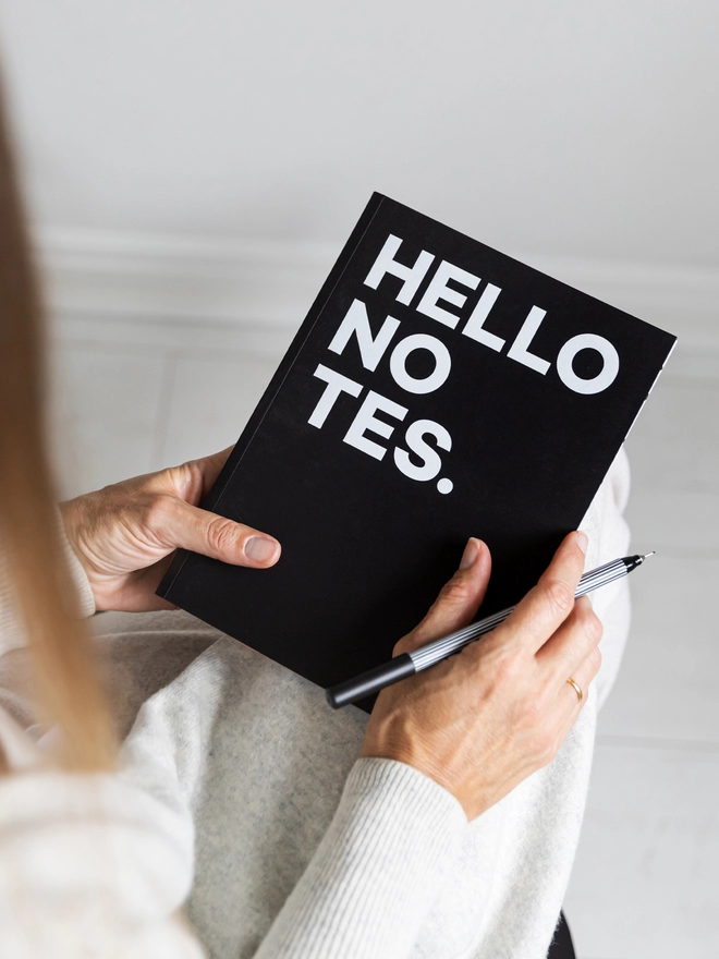 Lady holding a Hello Notes A5 Notebook and pen.