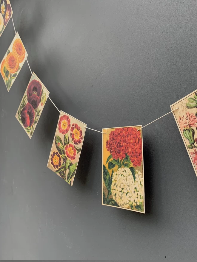 A string of paper bunting with vintage florals against a grey painted wall