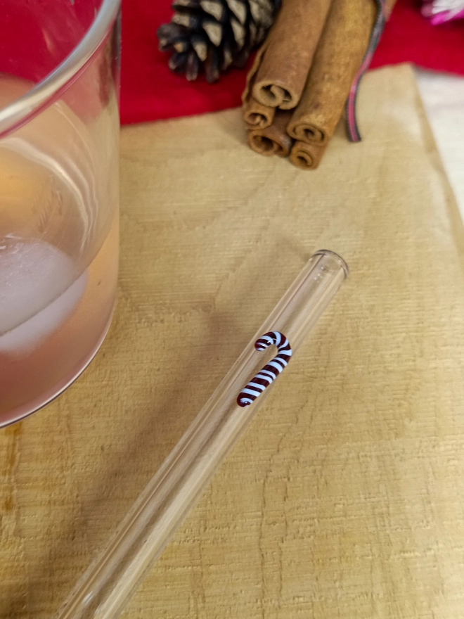 candy cane straw laid on a christmas layout next to a glass