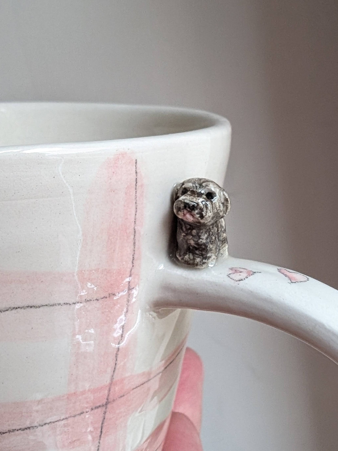 pink gingham cup with a tiny brown toy poodle dog and pawprints and hearts held in a hand looking rather lovely