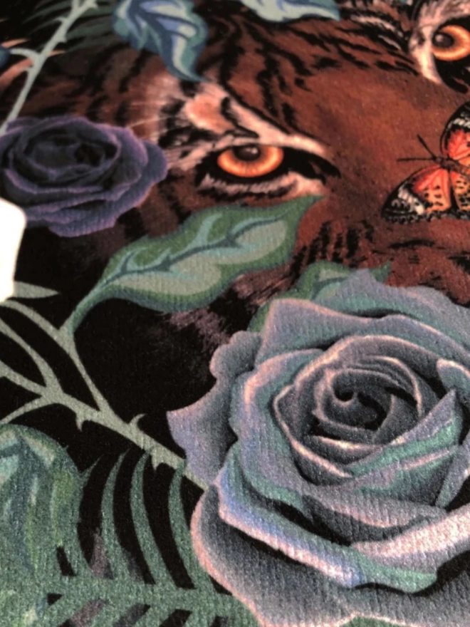 A close up of the floral velvet showing blue roses with a tiger with a butterfly on its nose