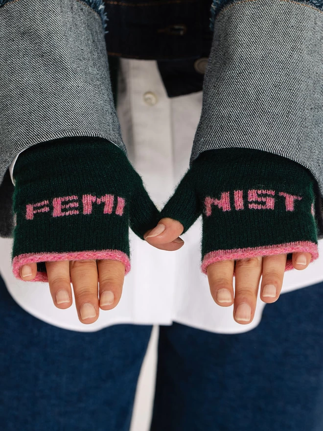 Feminist Fingerless Mittens in Forest Green on a white womans hands
