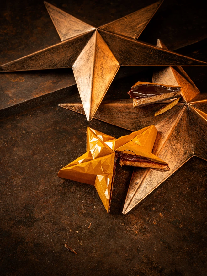 Shiny Golden Christmas star chocolate cut, showing dark chocolate and gingerbread cookie inside
