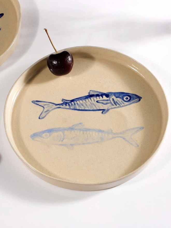 Handmade Ceramic Side Plate With 2 Blue Sardines Design, a white ceramic side plate sitting on a white table surface. 