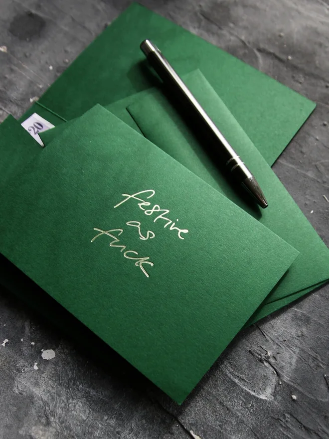 Hand foiled cash card or money wallet in a forest green colour handfoiled in shiny lime green text which says 'festive as fuck'.