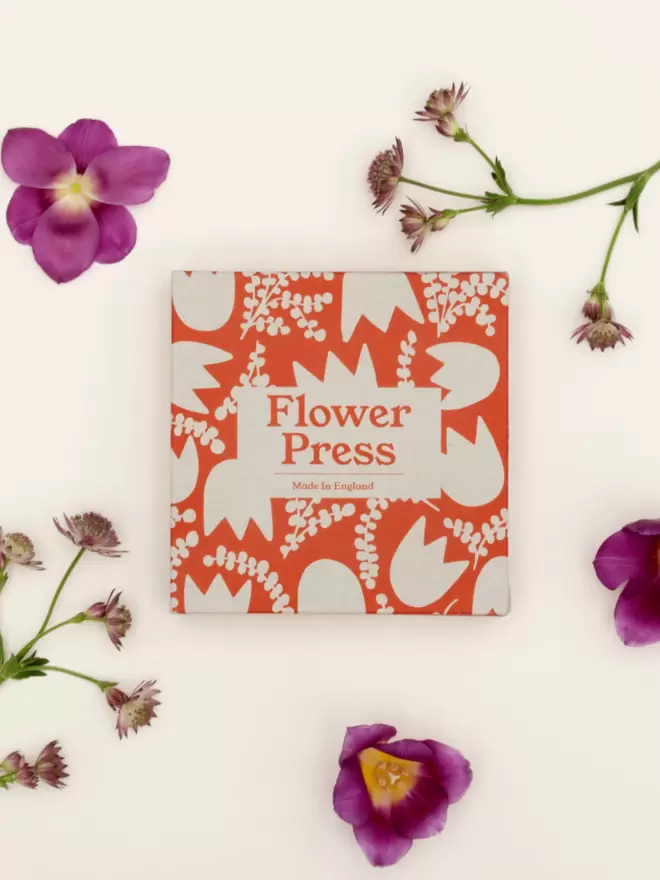 Flower press in colourful abstract floral printed box, surrounded by tulips.