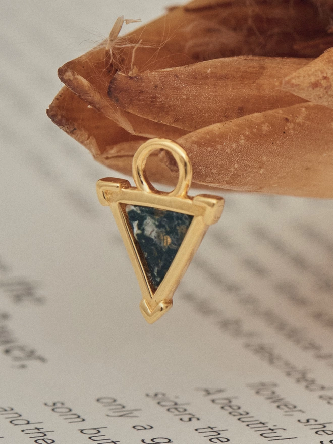 close up of Dendritic Shield gold Charm featuring a slice of dendritic chaceldony stone