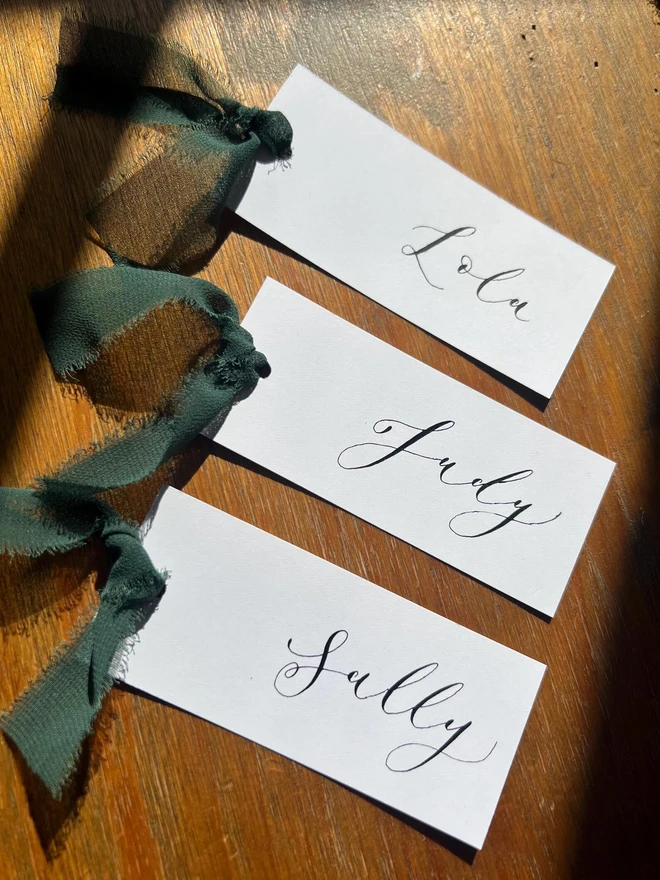Personalised Calligraphy Wedding White Place Cards, white place cards with forest green ribbon. 