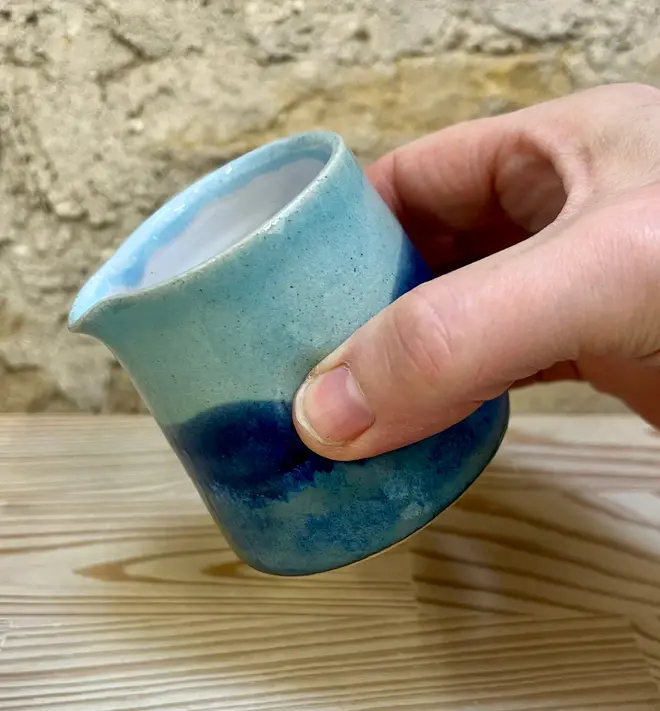 Landscape Tiny Jug, a colourful jug being poured against a brick wall. 