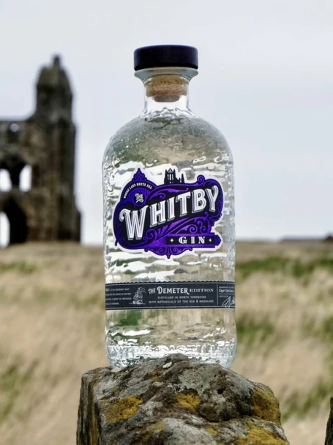 The Demeter Edition Gin, a bottle of gin sitting outside on a rock. 