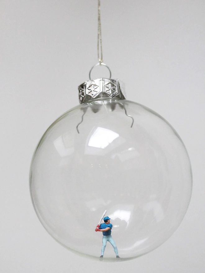 Miniature figure of a baseball player in a glass Christmas bauble 