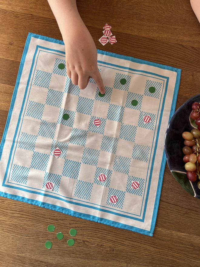A child playing draughts using Mr.PS Checkerboard Napkin with the cut out counters