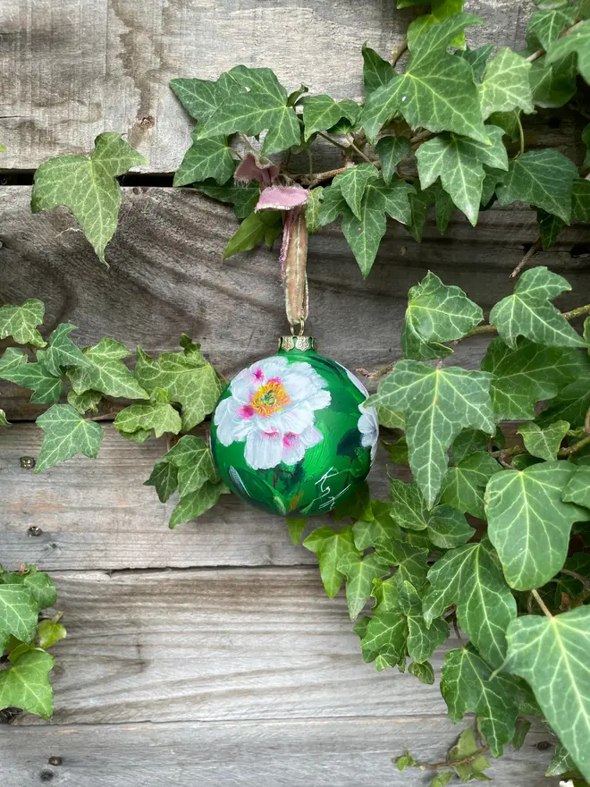 Hand painted floral ceramic bauble green background adorned in tree peony flowers