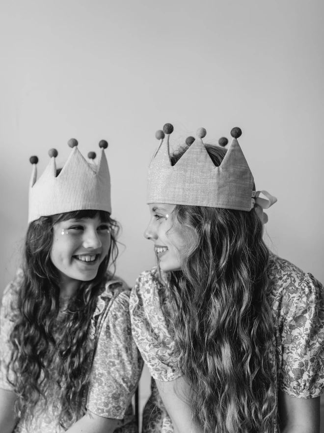 Two girls looking at each other so happy in their handmade fancy dress crowns 