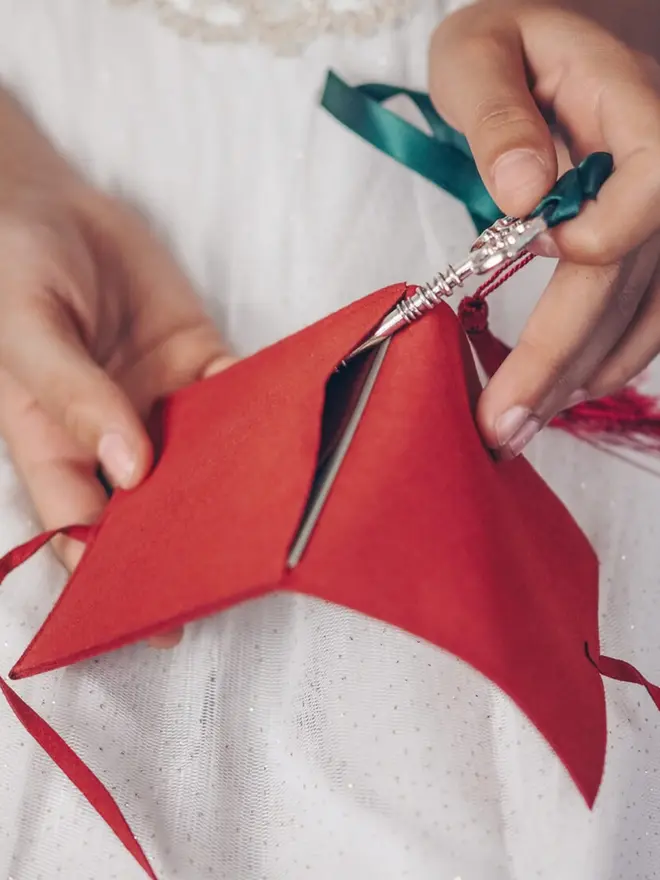Hands slide the silver key into its red suede pouch. The note says to keep the key there so it works year after year.