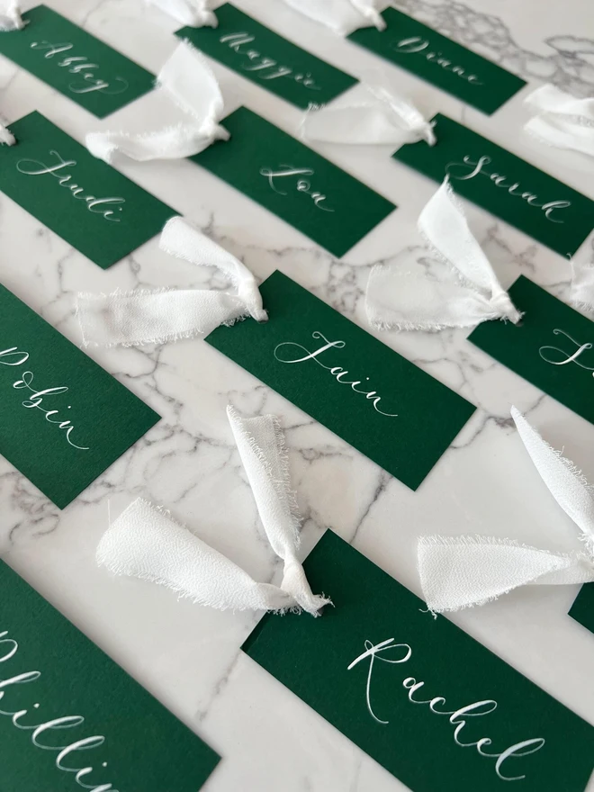 Personalised Calligraphy Wedding Green Place Cards, grouped together with white ribbon. 