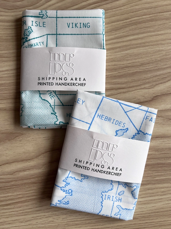Mr.PS Shipping Handkerchiefs folded and wrapped in packets on a wooden table