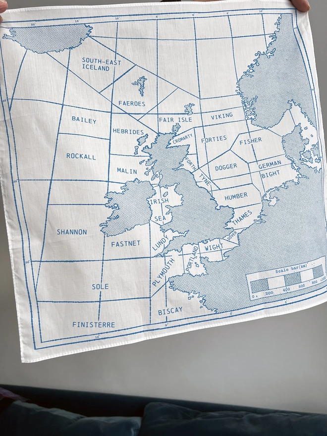 A Mr.PS Shipping Area Handkerchief held aloft above a blue sofa