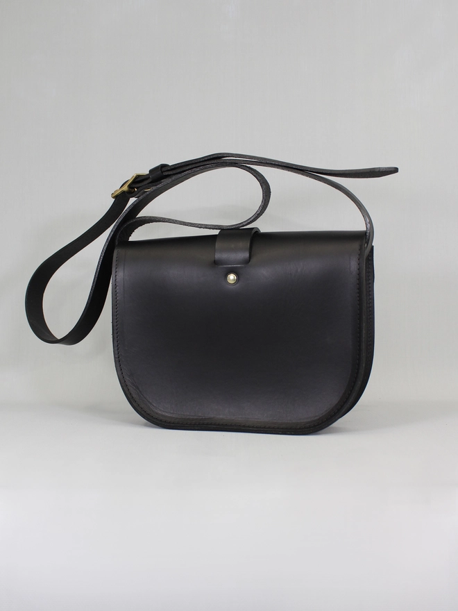 the reverse of a women's black leather vegtan saddlebag with botanical artwork by natthakur