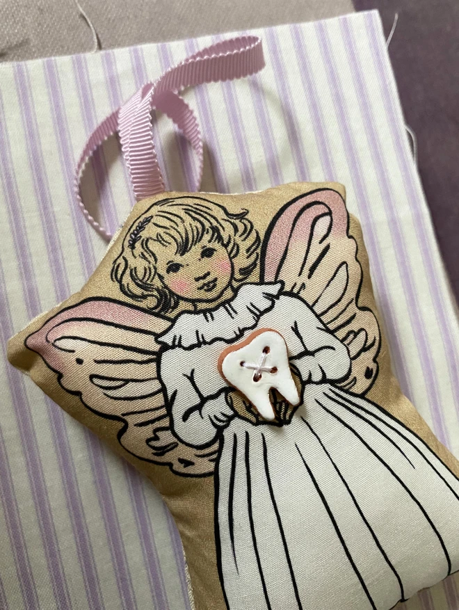 a close up of a tooth fairy holding a tooth ceramic button